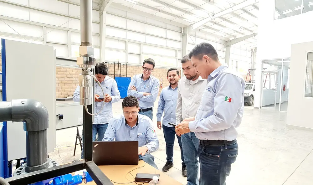 Equipo técnico revisando la configuración de un medidor con una laptop durante una capacitación